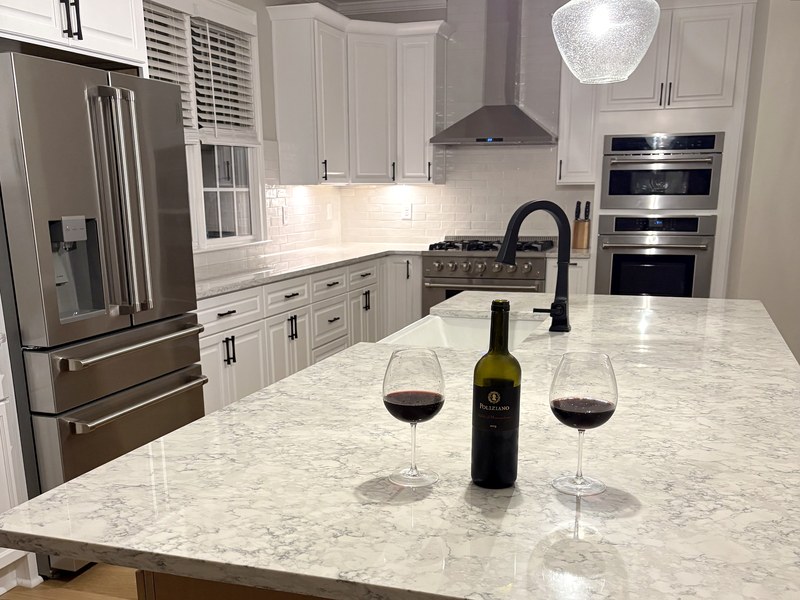 Custom white kitchen with a warm-wood island, natural-stone counters, and a professional gas range — a RYMAC kitchen remodel in Milton, GA.