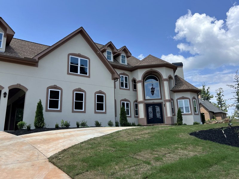 Finished, landscaped front elevation of a large custom stucco home with an arched entry — a 5,876 sq ft RYMAC custom home in Gainesville, GA.